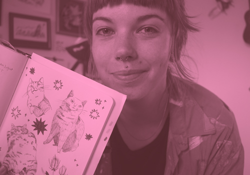 Cat illustrator and graphic designer Johanna Breuch holding up her sketchbook with cat drawings in it